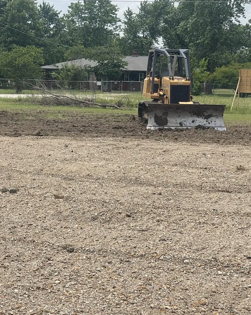 Dozer leveling a crushed rock pad in front of a house